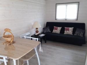 a living room with a black couch and a table at Petit Chalet Chez Marcelline in Amécourt