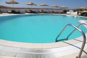 a large blue swimming pool with chairs and umbrellas at Castellano Village in Analipsi