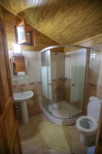a bathroom with a shower and a toilet and a sink at Ugur Pansiyon Bungalows in Cıralı +179 photos