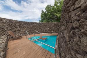 a swimming pool on a wooden deck next to a stone wall at Nayara Hangaroa in Hanga Roa