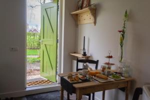 um quarto com uma mesa com pão e uma porta verde em 't Rheebokje em Uddel