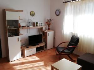 a living room with a television and a chair at Kod Male Gospe in Tribunj