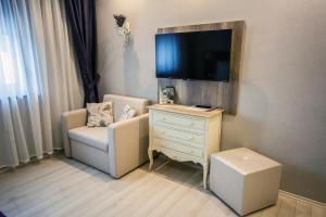 a room with a chair and a dresser with a tv at Levendula Apartmanház in Sárvár