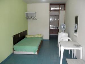 a bedroom with a bed and a table and a chair at Kit's Ubatuba in Ubatuba