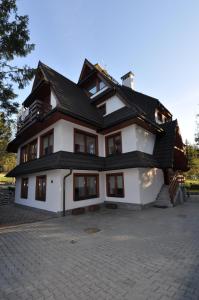 a large white house with a black roof at Apartament Zakątek Miętusi in Kościelisko