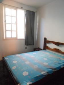 1 dormitorio con 1 cama con edredón azul y ventana en Casa de praia, en Salvador