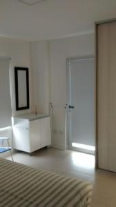 een witte slaapkamer met een bed en een spiegel bij Torre 1 Relax in Puerto Madryn