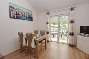 a dining room with a table and chairs and a television at Apartments Lorena in Mokošica