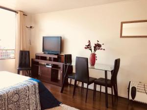 a bedroom with a dining room table and a television at Metro U de Chile Santiago Centro in Santiago