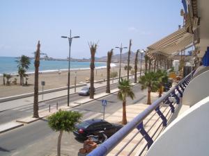 a balcony with a view of a beach and palm trees at Primerísima línea de playa in Carboneras