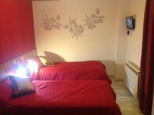 2 camas en una habitación pequeña con sábanas rojas en Hostal Neptuno, en Cáceres