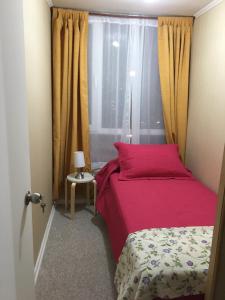 a small bedroom with a pink bed and a window at Departamento Puerto Montt in Puerto Montt