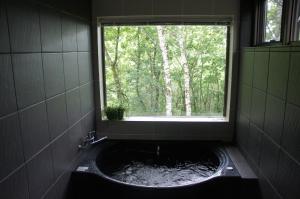 uma banheira na casa de banho com uma janela em Guesthouse Kreutzer em Chino