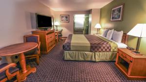 a hotel room with a bed and a table and a television at Chariot Inn Glendale - Pasadena in Glendale