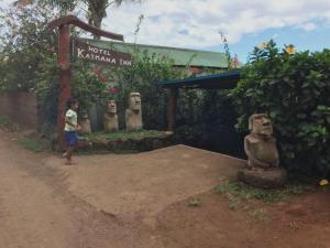 Kaimana Inn Rapa Nui في هانجا روا: بنت صغيرة تقف امام مجموعة تماثيل