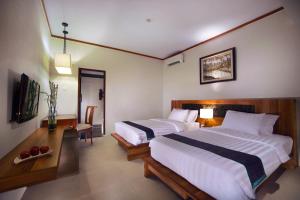 1 dormitorio con 2 camas, escritorio y TV en ASTON Sunset Beach Resort - Gili Trawangan, en Gili Trawangan