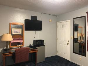 a hotel room with a desk and a television on the wall at Travelers INN in West Sacramento