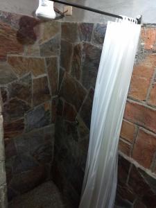 a shower curtain in a bathroom with a stone wall at Posada Don Jose in El Fuerte