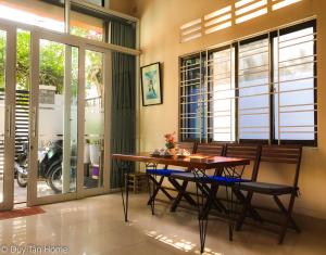 a dining room with a table and chairs and windows at Duy Tan Home in Quy Nhon