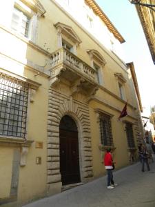 une femme debout en face d'un bâtiment avec balcon dans l'établissement Mezzanino L Palazzo Gagnoni Grugni, à Montepulciano