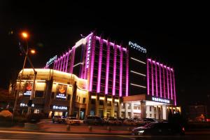 a building with purple lights on the side of it at Pullman Qingdao Ziyue in Qingdao