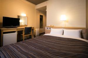 a hotel room with a bed and a desk with a television at Ark Hotel Okayama -ROUTE INN HOTELS- in Okayama