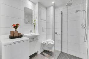 a white bathroom with a toilet and a sink and a shower at Forenom Serviced Apartments Oslo Rosenhoff in Oslo +21 photos
