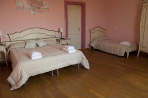 two beds in a room with pink walls and wooden floors at Locanda Corte Roveri in Bologna