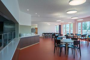 a dining room with tables and chairs and windows at Zug Youth Hostel in Zug