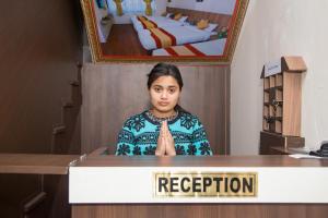 a woman standing behind a podium with a sign that reads reception at Sakura Boutique Hotel in Kathmandu