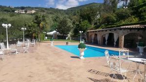 B&B La Mimosa في San Pietro: حمام سباحة مع مجموعة من الكراسي البيضاء وطاولة