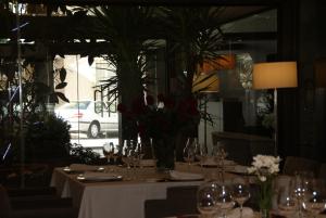 a table with glasses and a vase of flowers on it at Hotel Paloma in Tomelloso