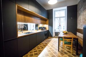 a kitchen with black cabinets and a wooden table at Warsaw Center 110 m2 Spacious and Elegant Apartment in Warsaw +48 photos
