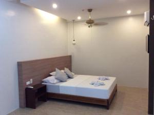 1 dormitorio con 1 cama con sábanas y almohadas blancas en La Casa Teresa Tourist Inn Inc, en El Nido