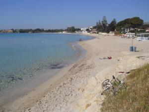 a bike parked on a sandy beach next to the water at Summer Beach Rooms in Fontane Bianche