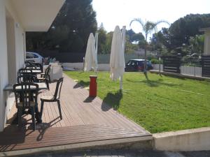 a deck with tables and white umbrellas and grass at Summer Beach Rooms in Fontane Bianche