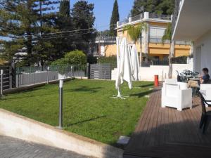 a patio with a lawn with a white umbrella at Summer Beach Rooms in Fontane Bianche