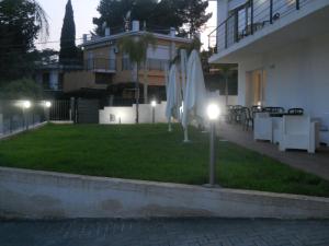 a lawn with umbrellas and tables and a building at Summer Beach Rooms in Fontane Bianche