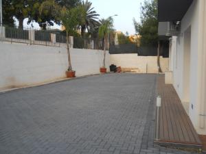 an empty parking lot with a white wall and palm trees at Summer Beach Rooms in Fontane Bianche