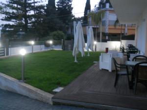 a patio with tables and white umbrellas on a lawn at Summer Beach Rooms in Fontane Bianche