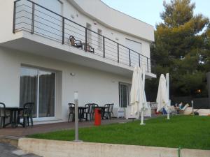 a house with a balcony with tables and umbrellas at Summer Beach Rooms in Fontane Bianche