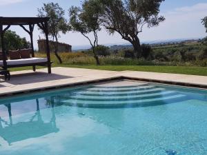 a swimming pool with a chair and a gazebo at Terre Di Vendicari in Noto