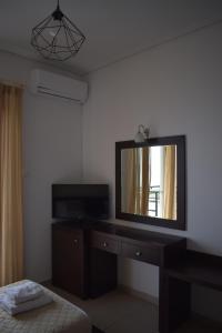 a room with a mirror and a dresser with a television at Tokalis Boutique Hotel & Spa in Nea Anchialos