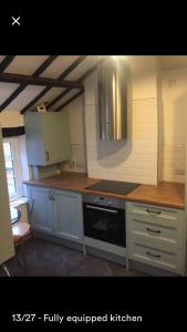 a kitchen with white cabinets and a stove top oven at Kenilworth Cosy Garden View Apartment in Kenilworth