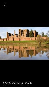 un castillo se refleja en un cuerpo de agua en Kenilworth Cosy Garden View Apartment, en Kenilworth