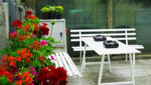 a white bench next to a table and flowers at Giovanna Rooms in Caorle +5 photos
