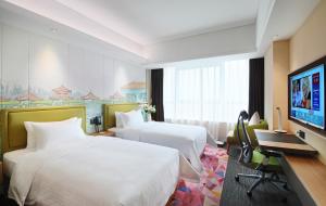 a hotel room with two beds and a flat screen tv at Hampton By Hilton Foshan Sanshui in Foshan