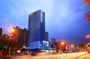 Un palazzo alto in una città di notte con traffico di Hampton By Hilton Foshan Sanshui a Foshan