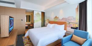 una camera da letto con un letto bianco e una sedia blu di Hampton By Hilton Foshan Sanshui a Foshan