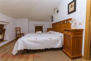una camera con un grande letto e un comò in legno di Casa Rural El Salon del Baile a Navarredondilla